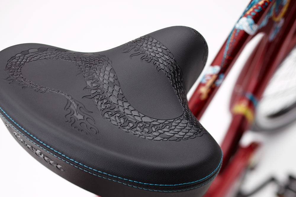 Close-up of a black bicycle seat with red frame in the background