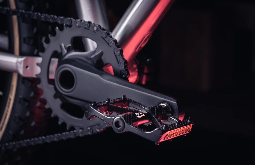 Close-up of a bicycle chain and gear system with red accents on a dark background