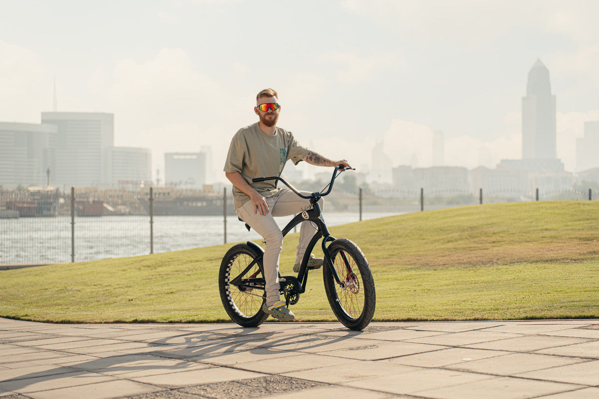 Man riding a bicycle on a path with a city skyline in the background