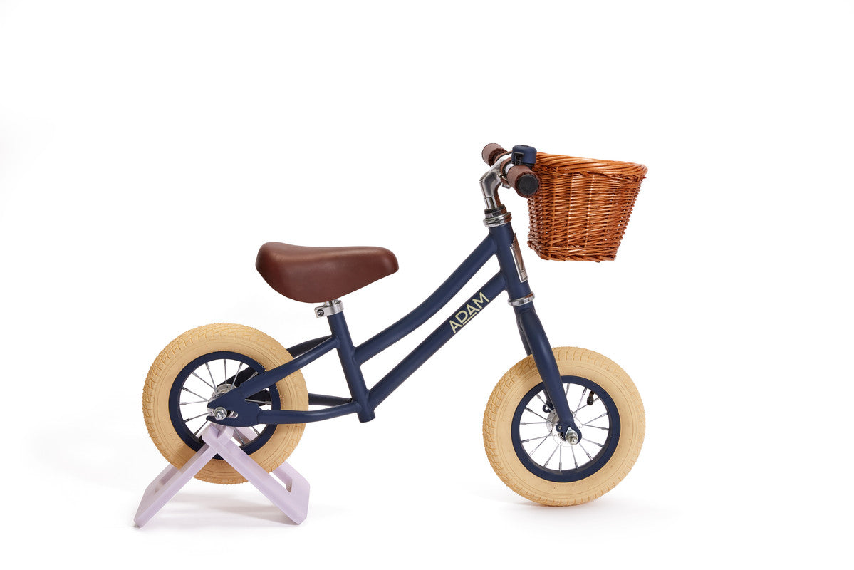 Navy balance bike with a brown basket on a white background