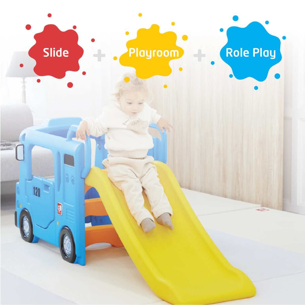 Child sliding down a yellow slide attached to a blue toy truck in a playroom.