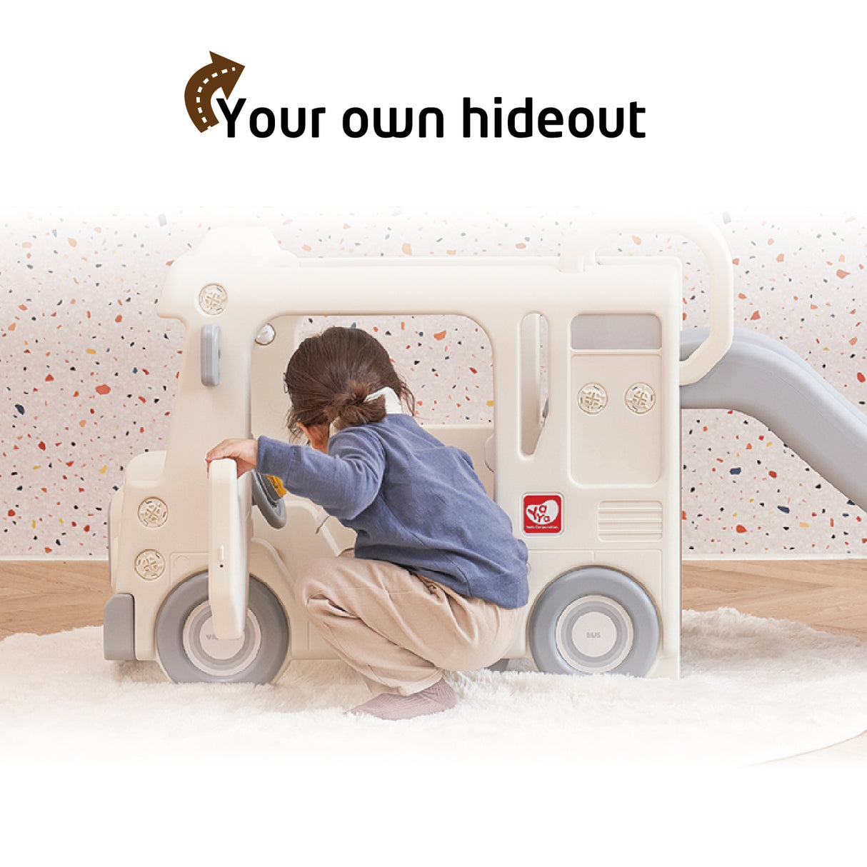 Child playing with a toy slide and swing set labeled 'Your own hideout' on a light-colored background.