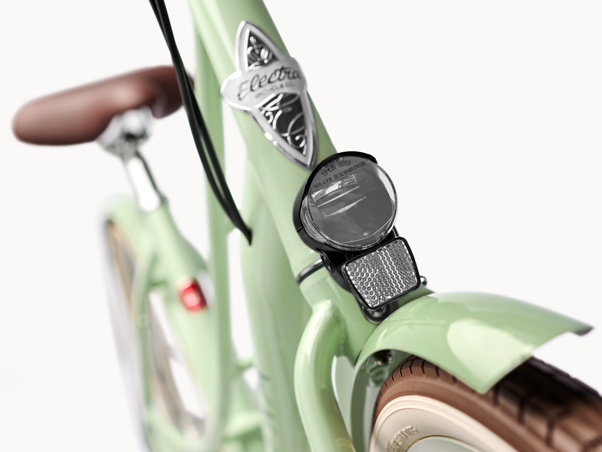 Close-up of a light green bicycle with a headlight and brand logo on a white background