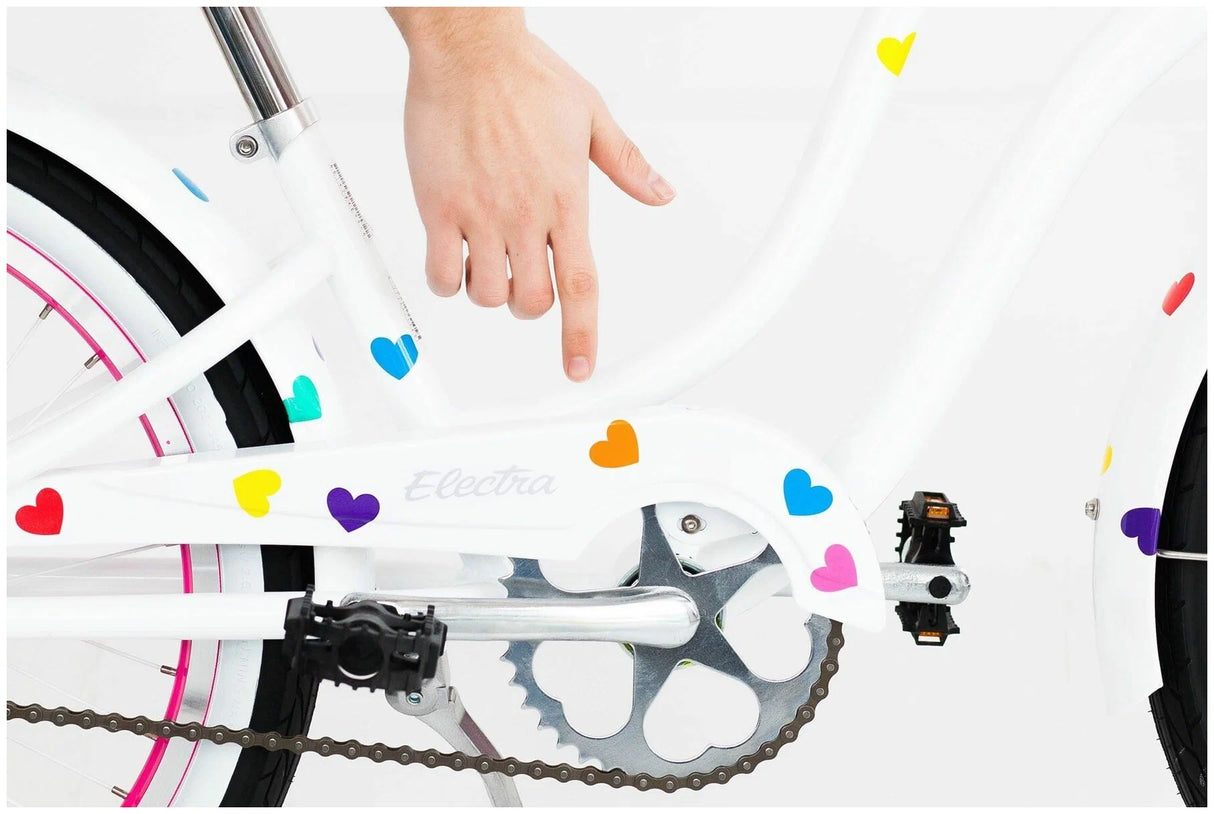 Close-up of a bicycle wheel with colorful heart-shaped stickers on a white background