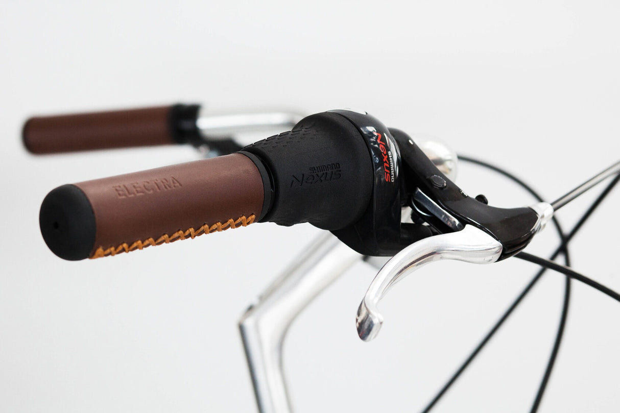 Close-up of bicycle handlebars with brown grips and black stem on a white background