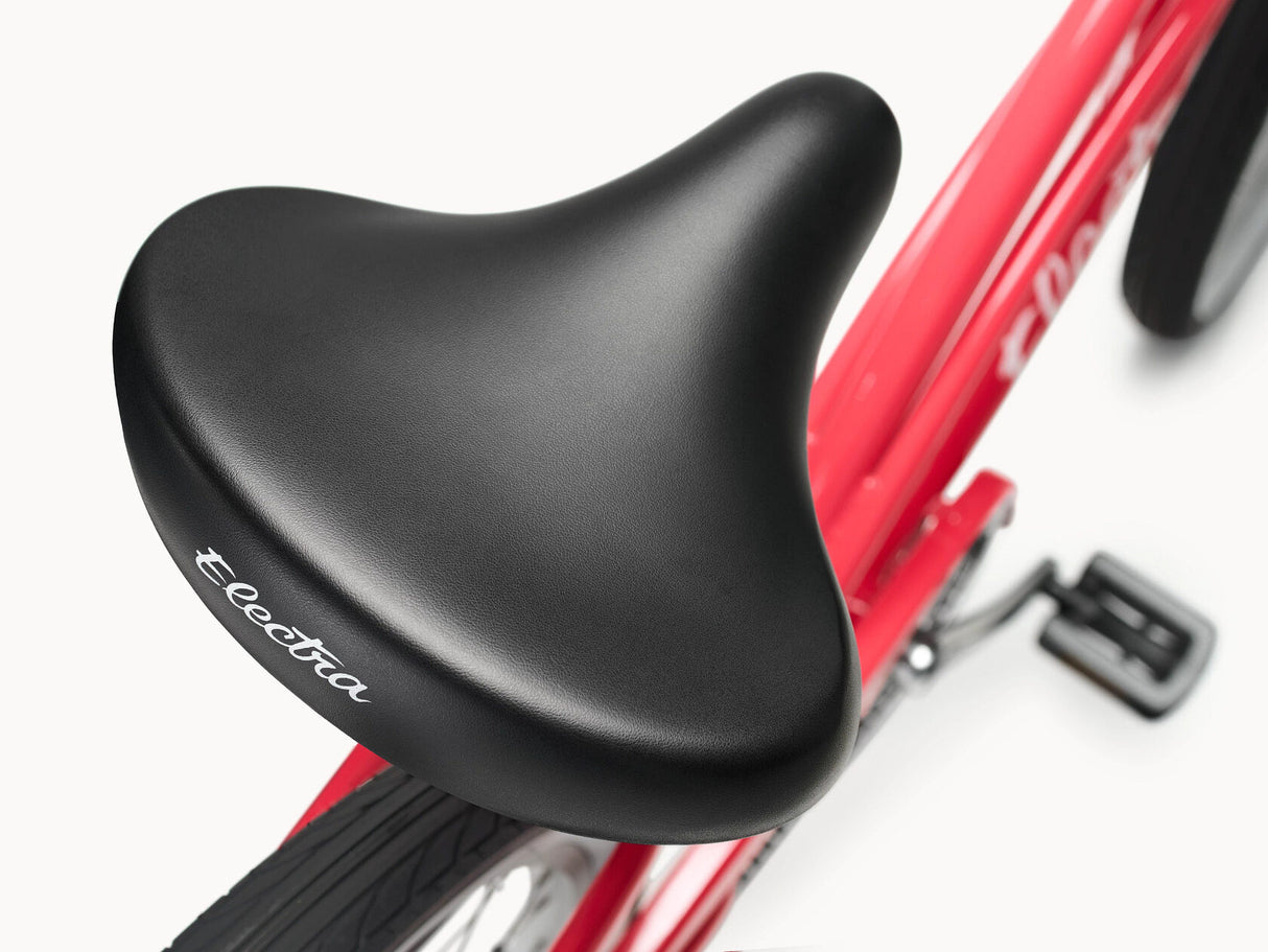 Close-up of a black bicycle seat on a red bike with 'Electra' branding.