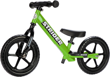 Green Strider balance bike on a white background