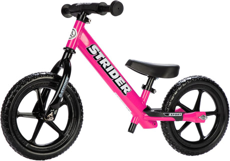 Pink balance bike with black seat and wheels on a white background