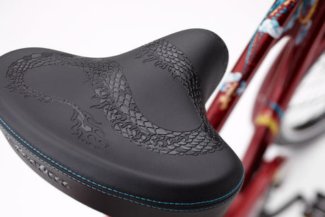 Close-up of a black bicycle seat with red frame in the background
