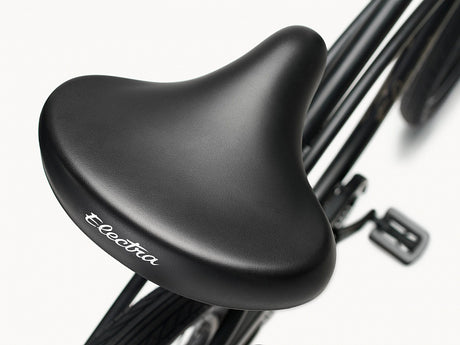 Close-up of a black bicycle seat with 'Electra' branding on a white background