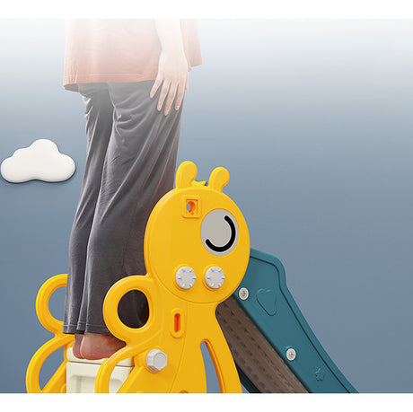 Child's feet standing on yellow honeybee-shaped steps with a blue slide in the background.