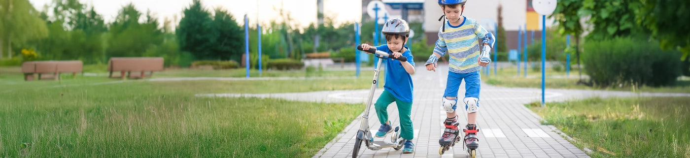 Two children on roller skates in a park with trees and benches in the background