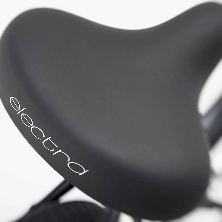 Close-up of a black bicycle seat with 'electra' branding on a white background