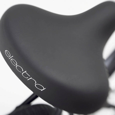 Close-up of a black bicycle seat with 'electra' branding on a white background