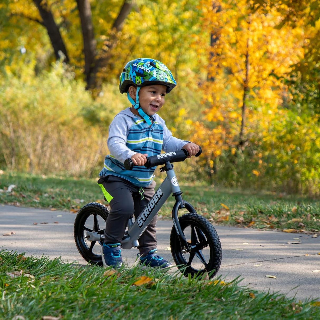 Child riding a balance bike in a park with autumn leaves