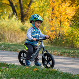 Child riding a balance bike in a park with autumn leaves